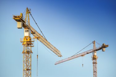 A genre photo of construction cranes in the sky.